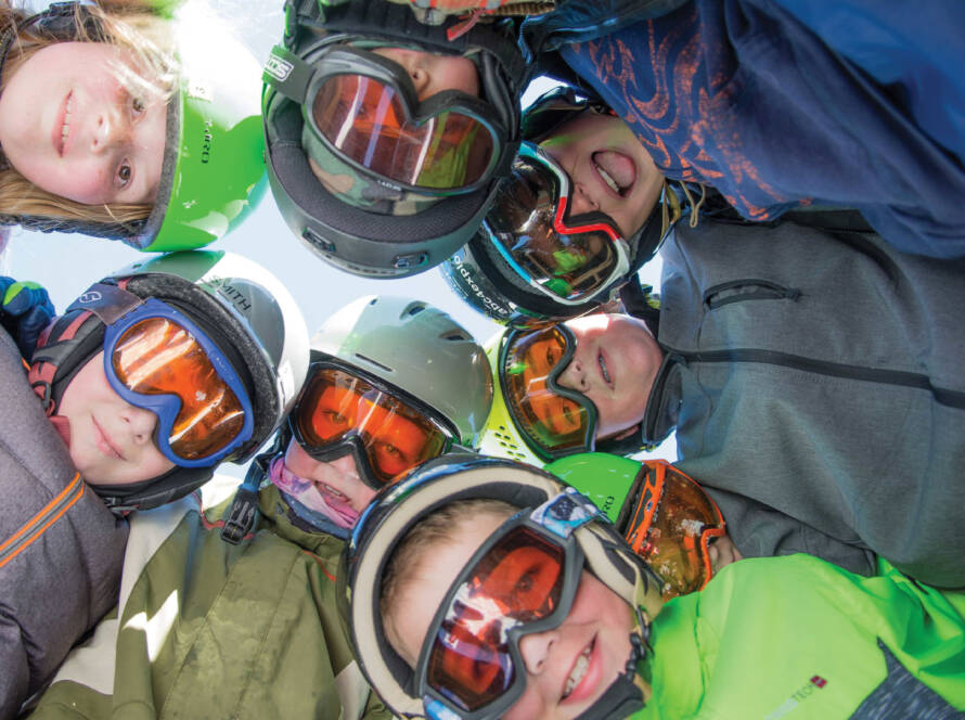 Group of young snow sports enthusiasts looking down at camera