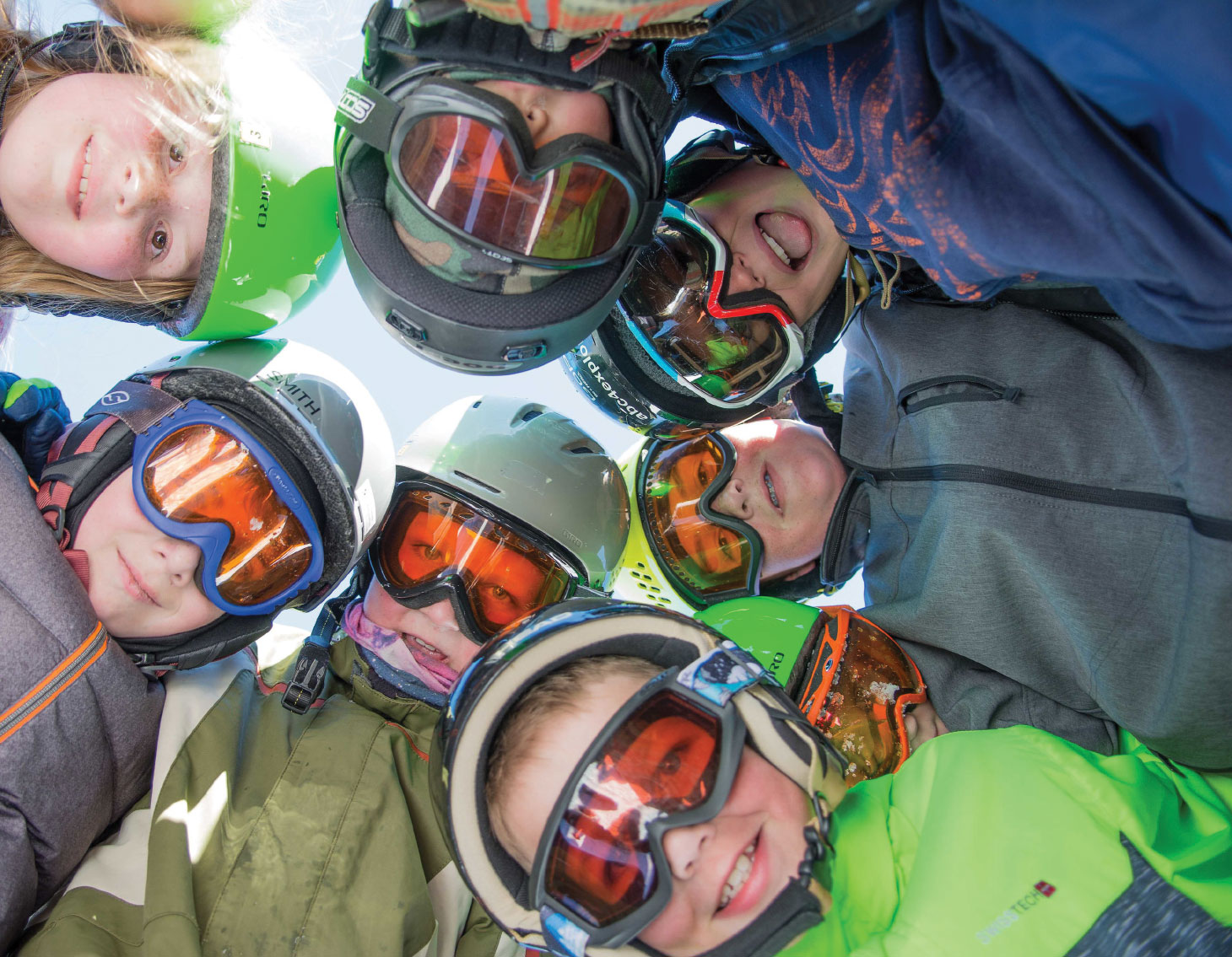 Group of young snow sports enthusiasts looking down at camera