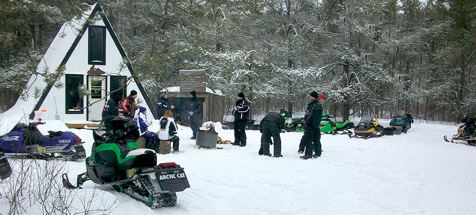 Snowmobile riders standing outside snow hut