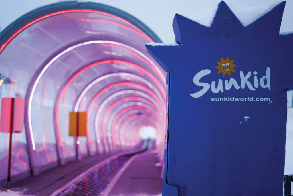 Inside view of moving carpet with plastic enclosure and lighting with Sunkid sign in foreground