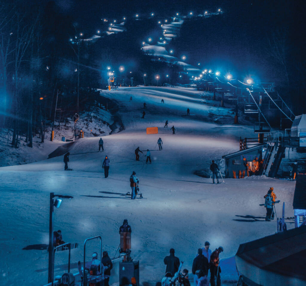 Skiers at night with lights on slopes
