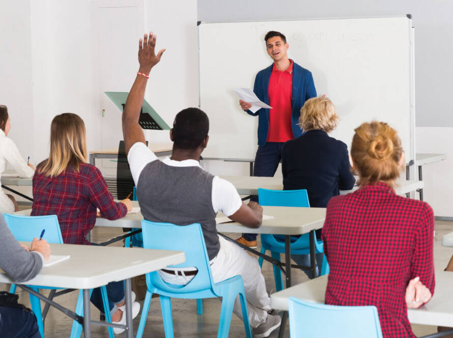 Teacher in class with student raising hand to ask a question