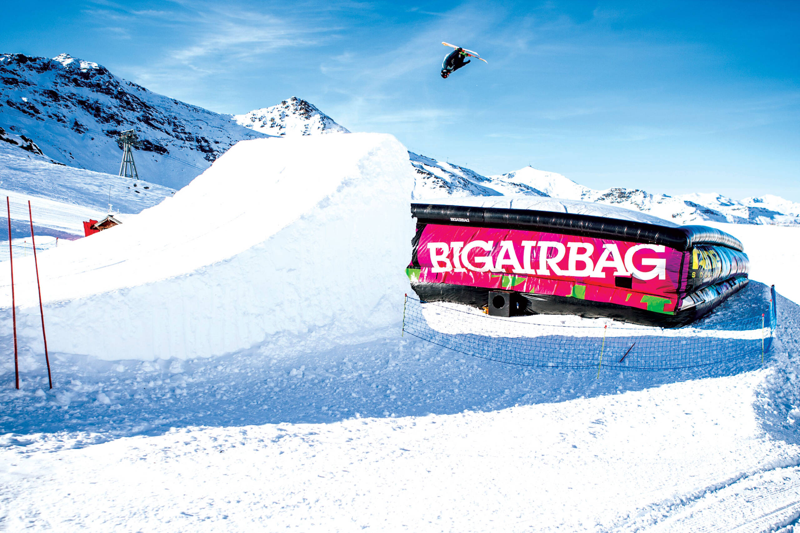 Snowboarder jumping off ramp on to BigAirBag
