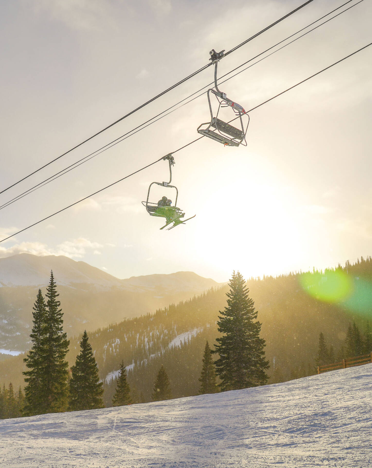 Skiers on chairlift with sunset in background