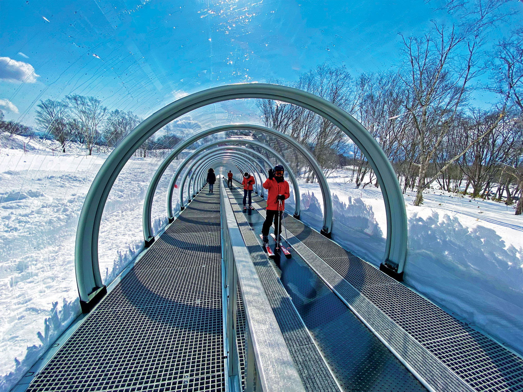 Skiers in a covered conveyor belt ski lift