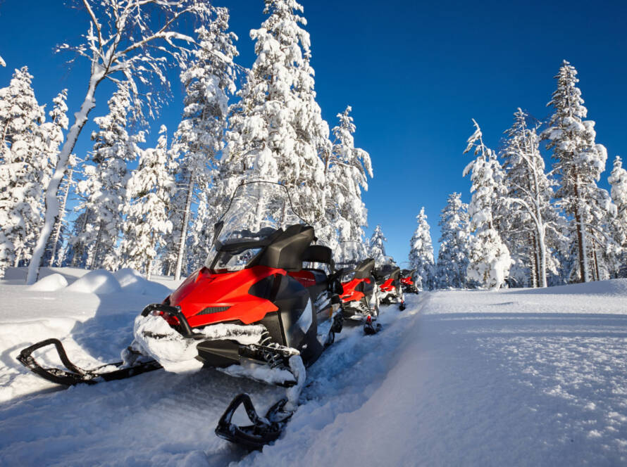 Snowmobile on trail with snow covered trees in background