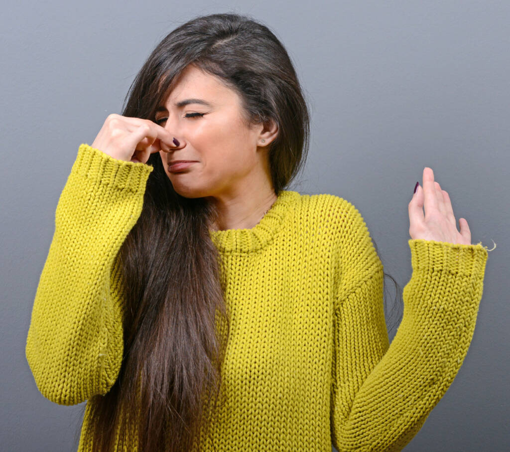 Girl in yellow sweater holding nose