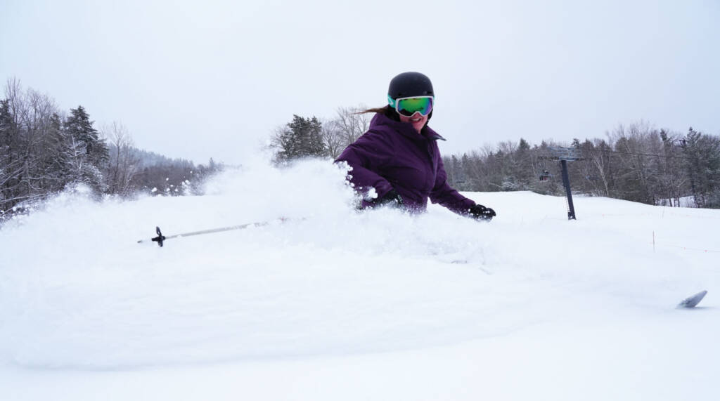 Woman on skis spraying snow towards camera