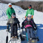Four skiers in snow gear and specialized ski equipment