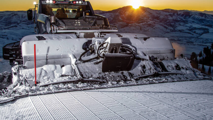 Prinoth snow groomer with sun setting in background