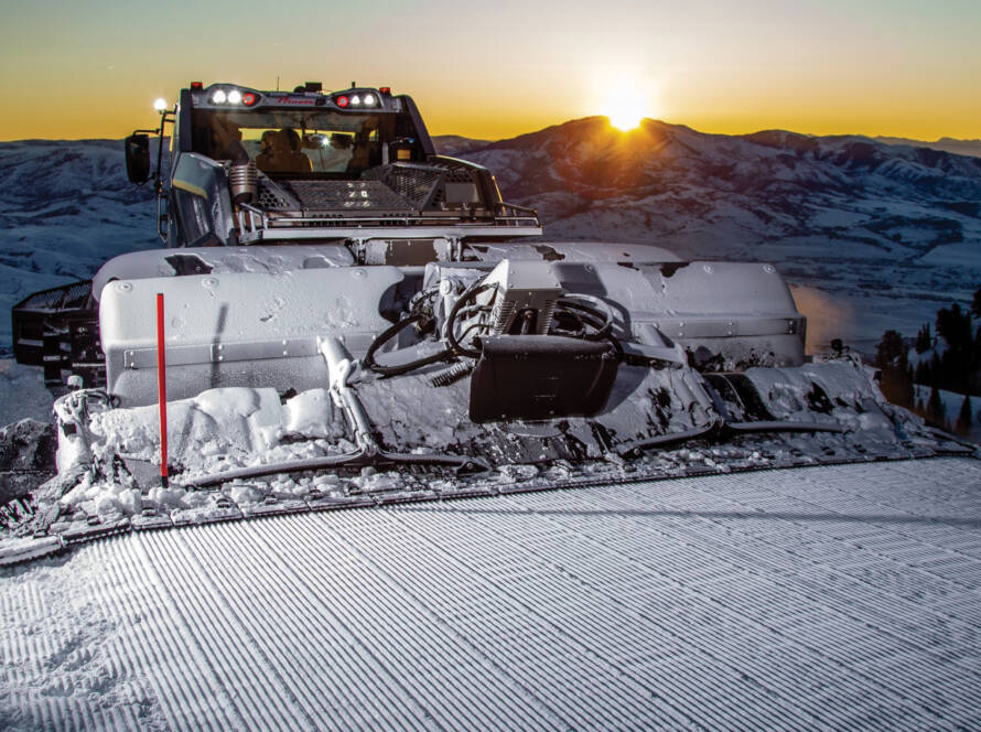 Prinoth snow groomer with sun setting in background