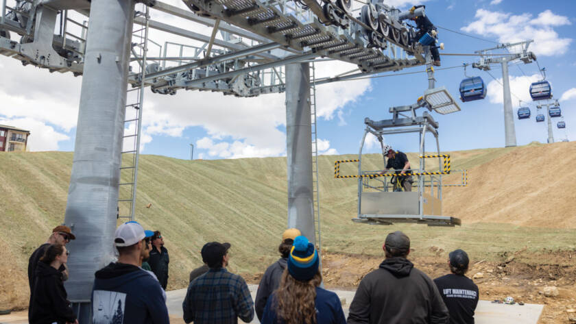 Students watching lift maintenance instructor on ski lift