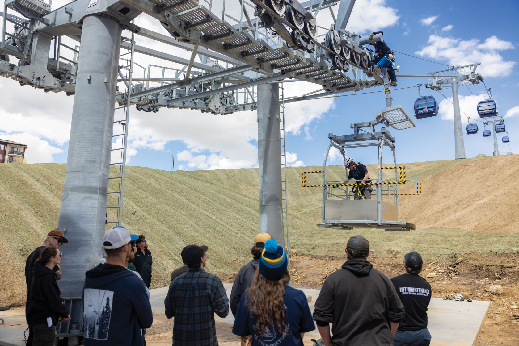 Students watching lift maintenance instructor on ski lift