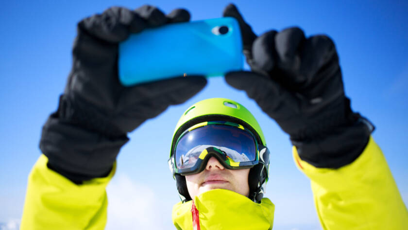 Person in snow suit taking photo or video with mobile phone