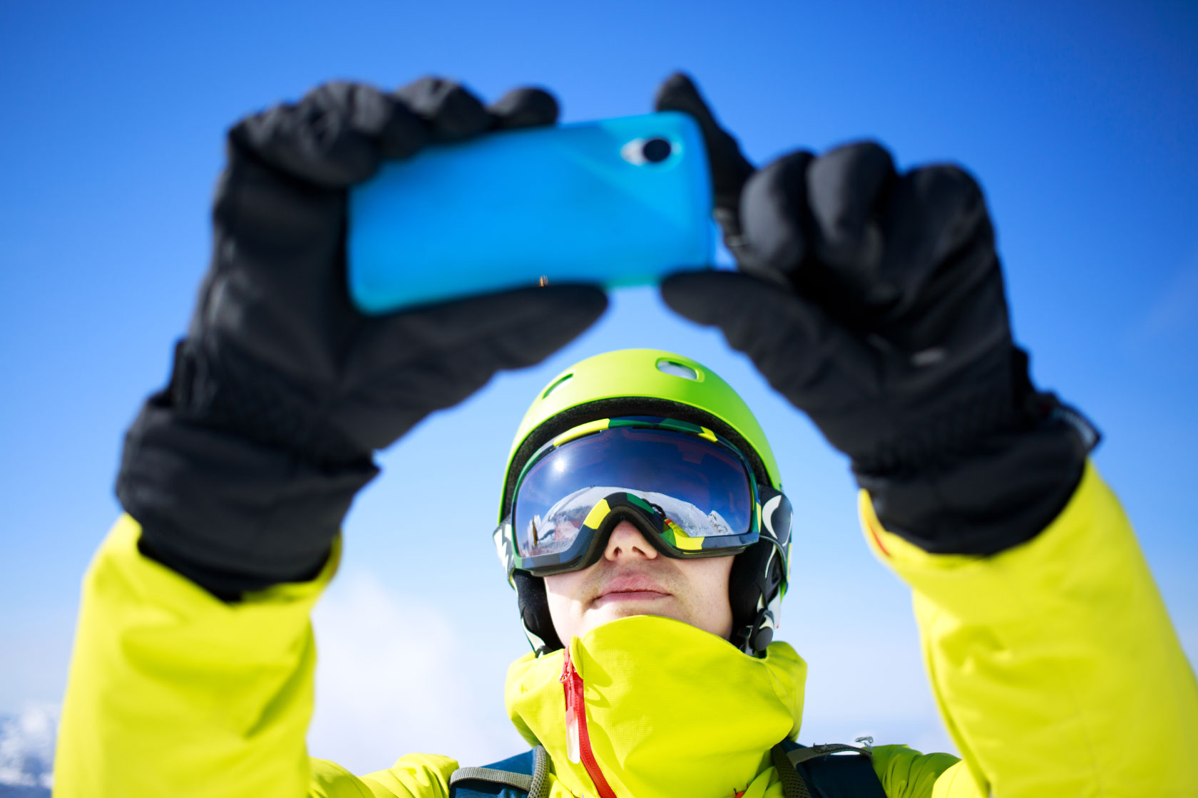 Person in snow suit taking photo or video with mobile phone