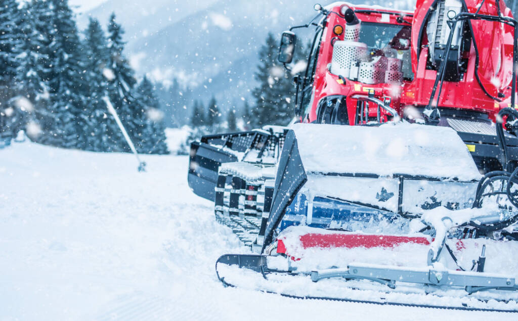 Snow groomer on mountain with falling snow