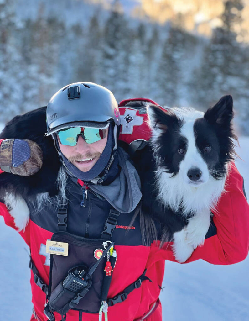 Daniel Linden in ski gear carrying dog on shoulders