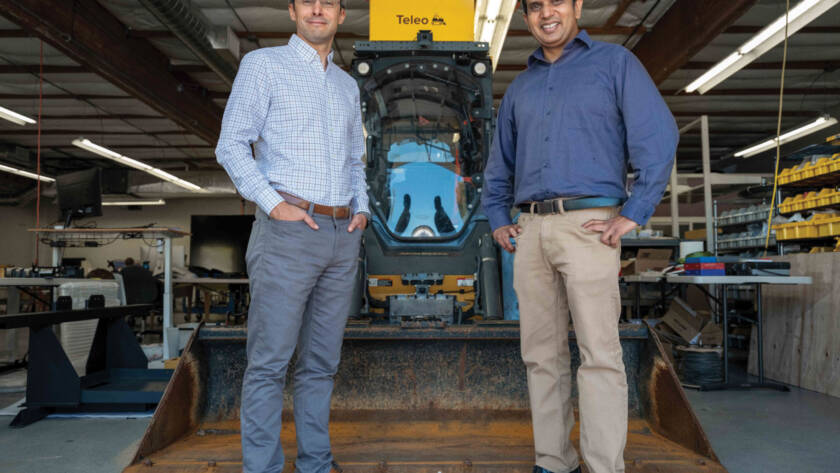 Rom Clément and Vinay Shet posing for photo in front of parked loader