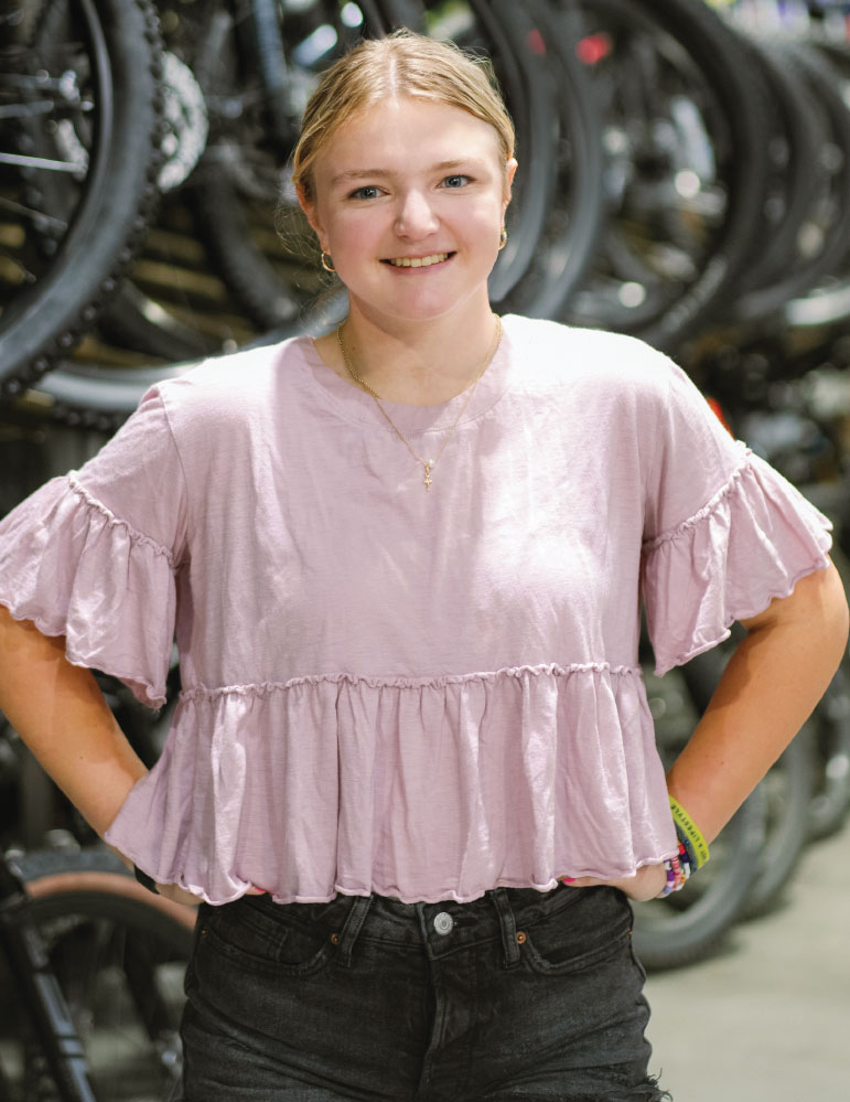 Samantha Braden posing with bicycles on racks in background